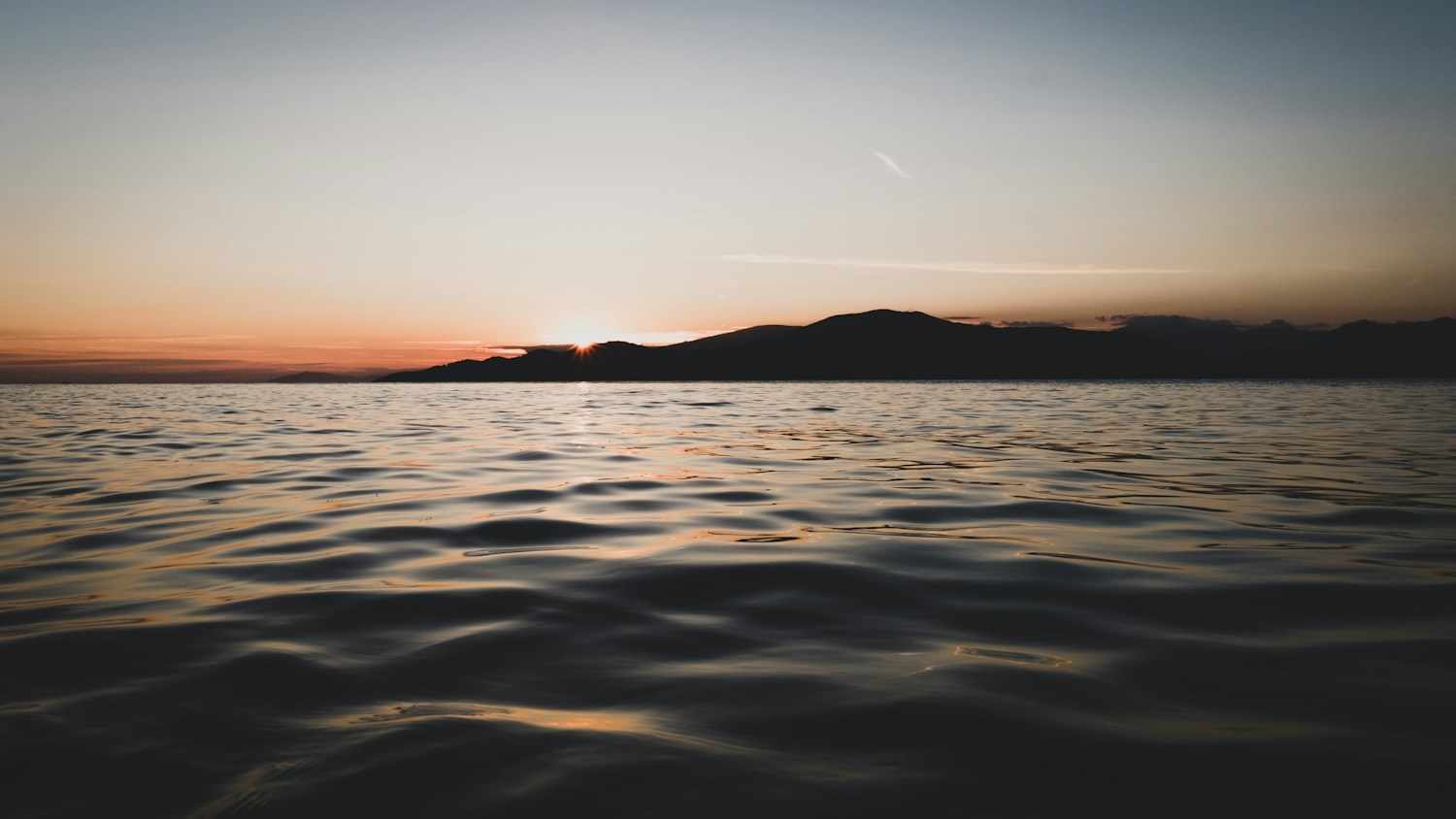 Evening light across a calm sea and distant mountains